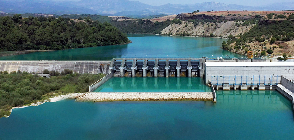 Aydem Holding'in Türkiye'nin 4 farklı bölgesinde yer alan santralleri temsil eden görsel yer almaktadır. Görselde dağların arasından geçen nehrin ortasında duran hidroelektrik santrali yer almaktadır.